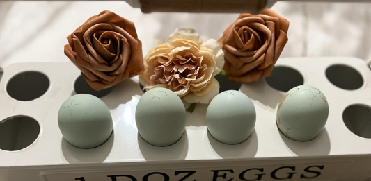 Blue Cream Legbar eggs in a carton with decorative flowers on top